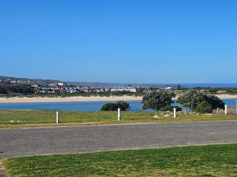 A scenic view overlooking a coastal landscape with a sandy beach, water, and distant residential development.