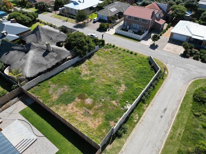 An aerial view of a vacant residential plot situated in a developed neighborhood, featuring established boundary walls and convenient street access.