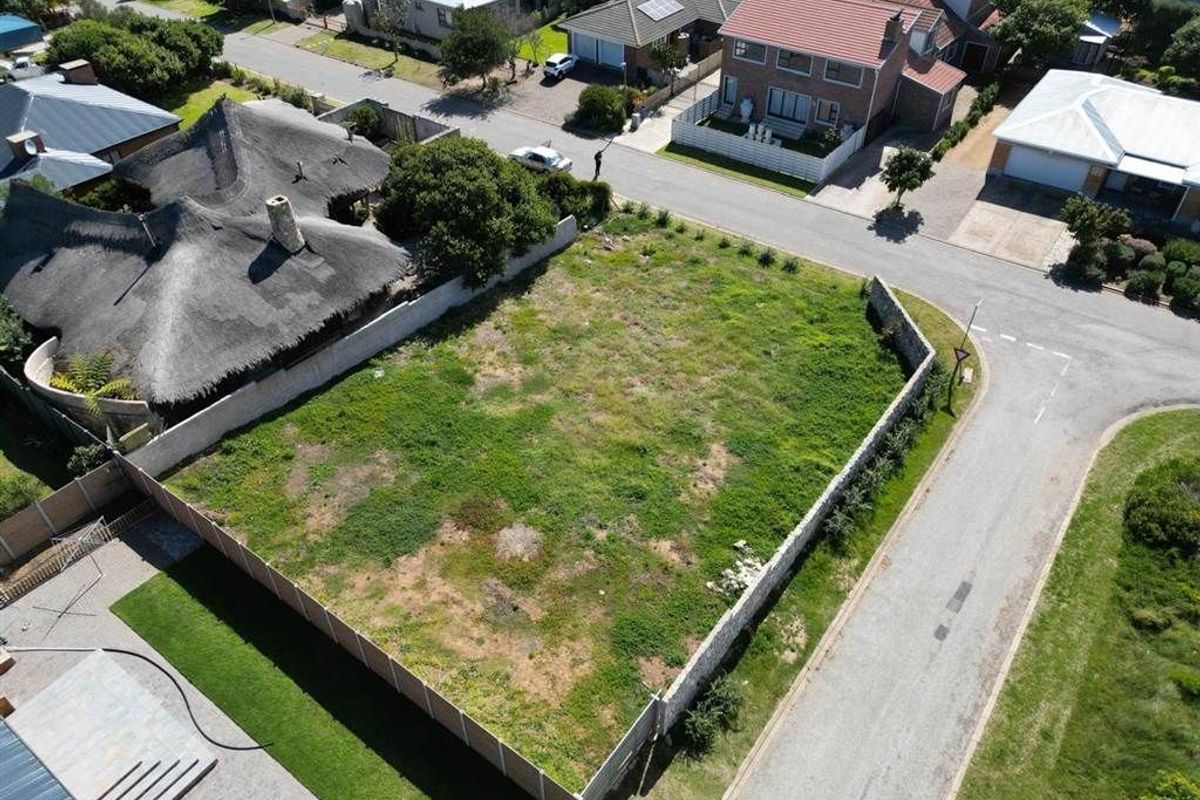 An aerial view of a vacant residential plot situated in a developed neighborhood, featuring established boundary walls and convenient street access.