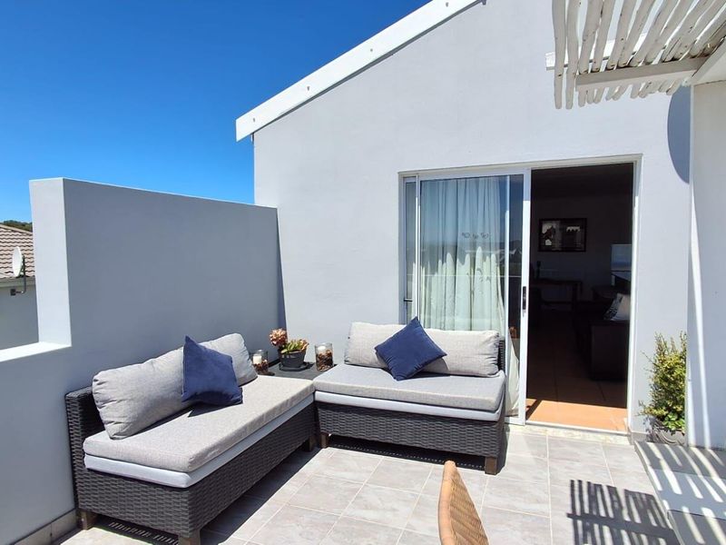 A well-maintained outdoor patio area featuring tiled flooring, a privacy wall, and a sliding glass door providing access to the interior living space.