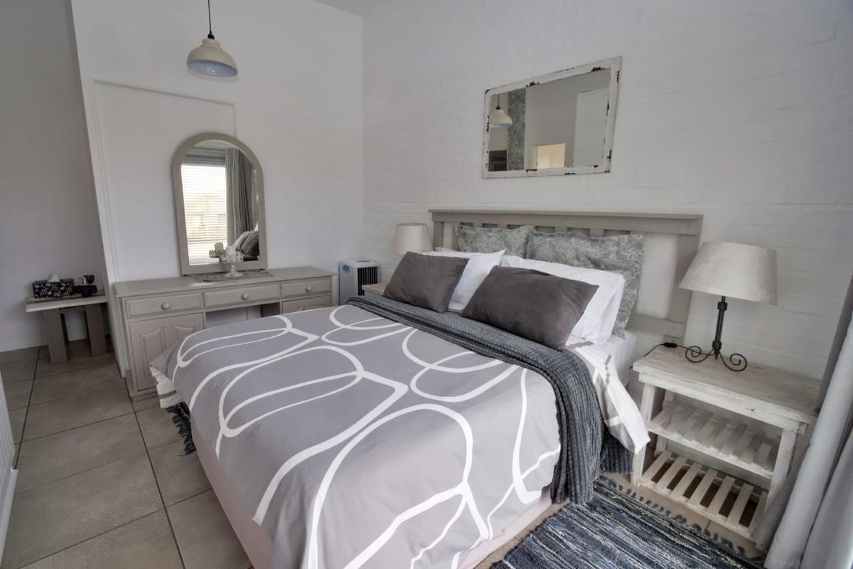 A well-maintained bedroom featuring tiled flooring, a painted brick feature wall, and neutral finishes, providing a comfortable and clean living space.