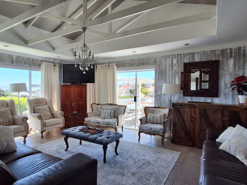 Spacious living room featuring a vaulted ceiling with exposed rafters, tiled flooring, and large sliding glass doors providing ample natural light and outdoor access.
