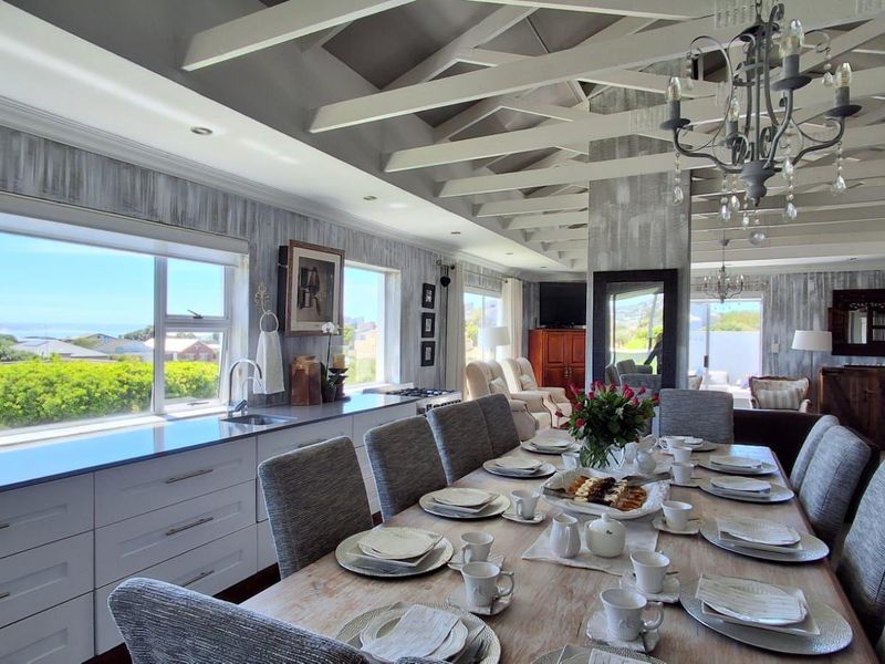 Spacious open-plan living and dining area featuring exposed timber ceiling beams, modern cabinetry, and large windows with scenic views.
