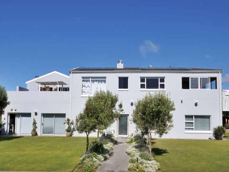A well-maintained two-story residential property featuring a landscaped garden, paved walkway, solar panels, and an upper-level balcony.