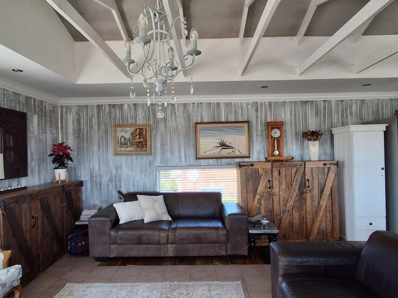 A living room featuring exposed white ceiling beams, tiled flooring, and decorative wall finishes, creating a rustic and cozy atmosphere.