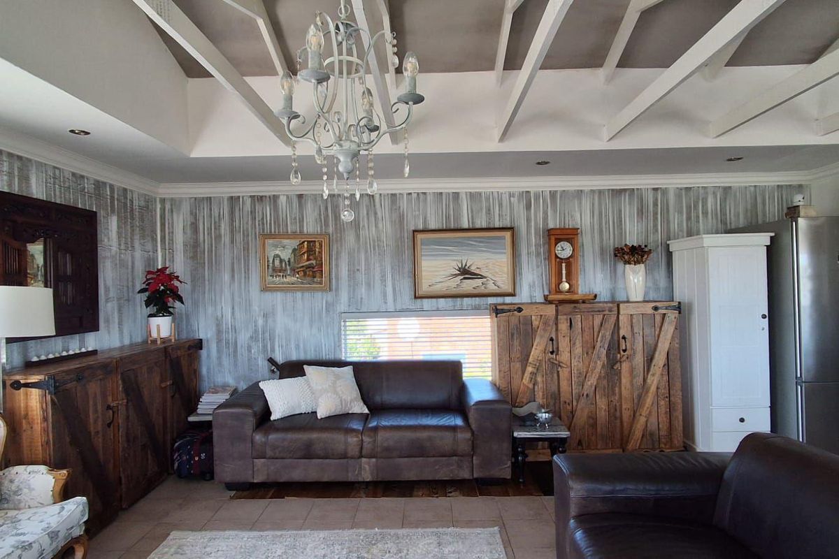 A living room featuring exposed white ceiling beams, tiled flooring, and decorative wall finishes, creating a rustic and cozy atmosphere.