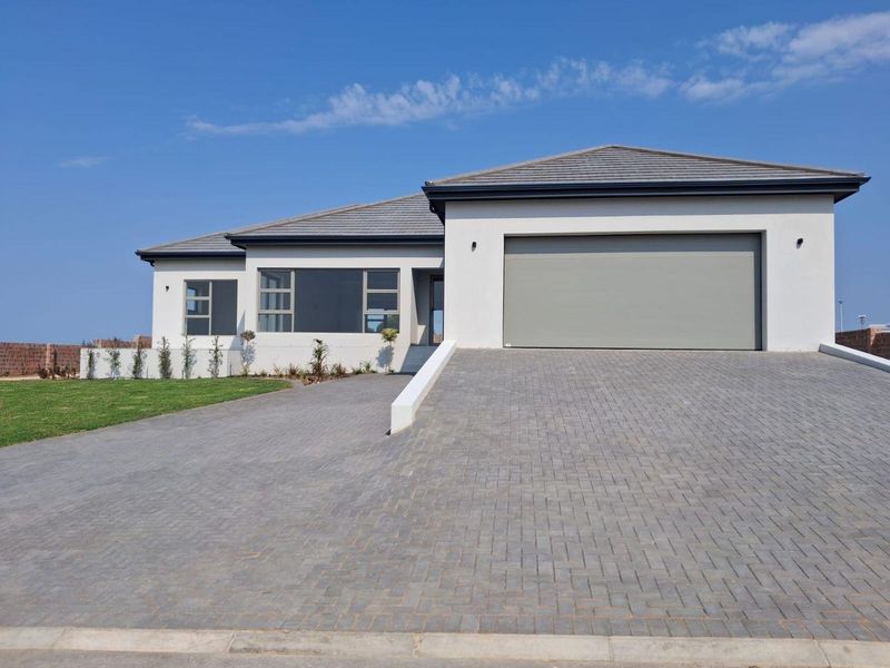 Modern single-story residential home featuring a paved driveway, automated garage, and clean architectural lines with a tiled roof.