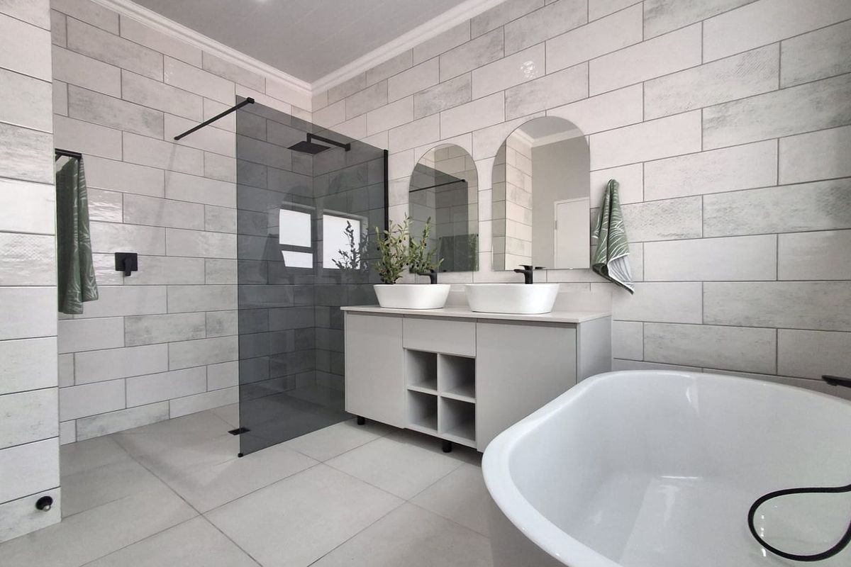 Modern, well-appointed bathroom featuring a double vanity, a sleek walk-in shower with glass screen, and a contemporary freestanding bathtub with high-quality tile finishes.