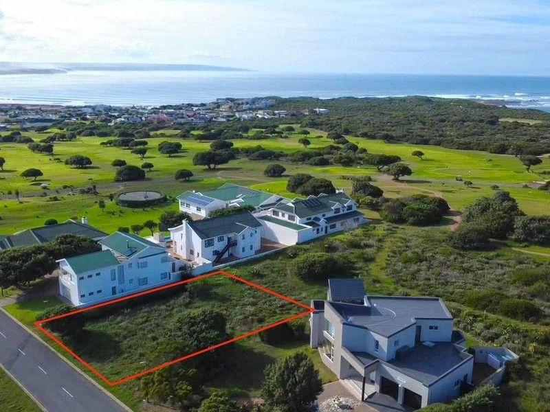 Aerial view of a vacant residential plot situated in a coastal estate, offering proximity to the ocean and surrounding green space.