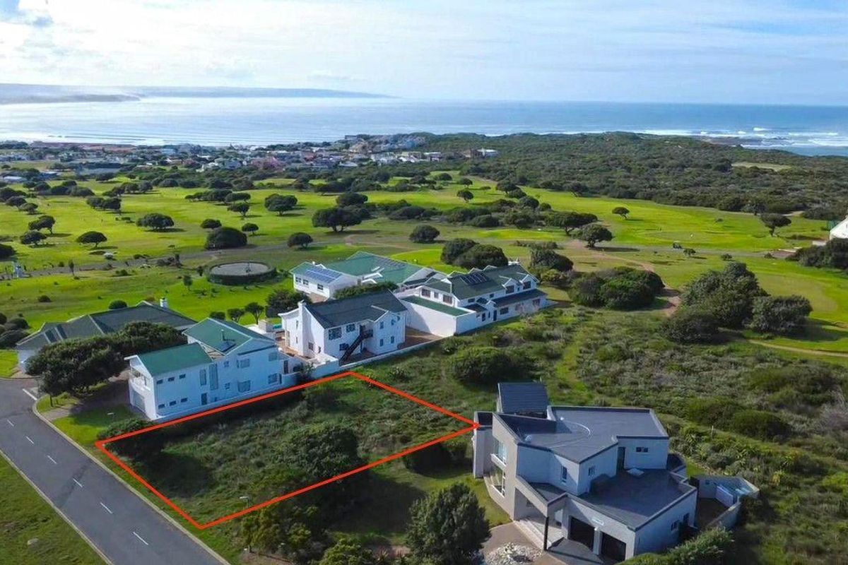 Aerial view of a vacant residential plot situated in a coastal estate, offering proximity to the ocean and surrounding green space.