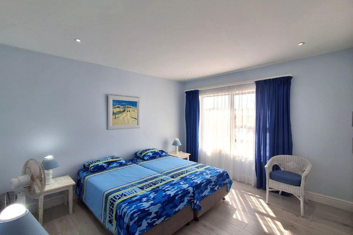 A well-maintained bedroom featuring light-toned laminate flooring and recessed downlighting, offering a bright and functional space.