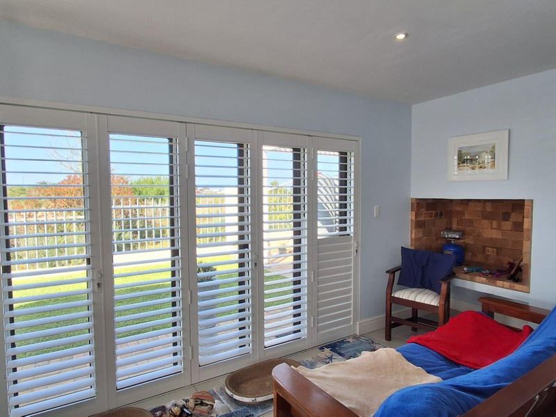 Living room featuring a wood-burning stove, recessed fireplace, and large bi-fold doors with plantation shutters opening to the garden.
