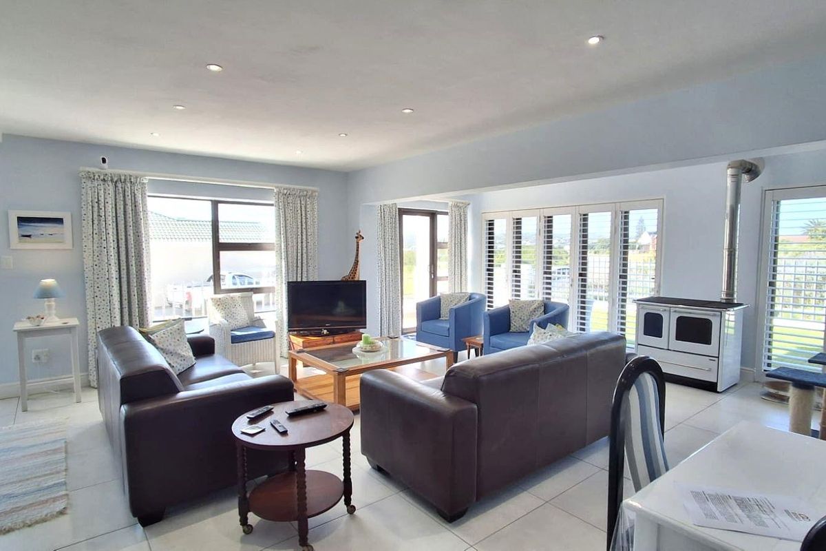 Spacious living room featuring tiled flooring, recessed lighting, and a freestanding wood-burning stove, with large windows and sliding doors providing ample natural light.
