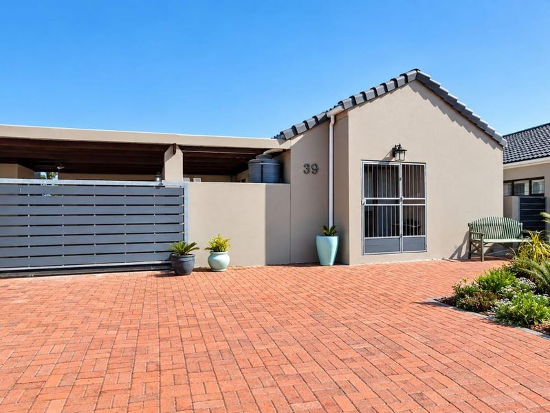 Front exterior view of the property featuring a brick paved driveway, a covered carport, and a secure entrance with a metal security gate.