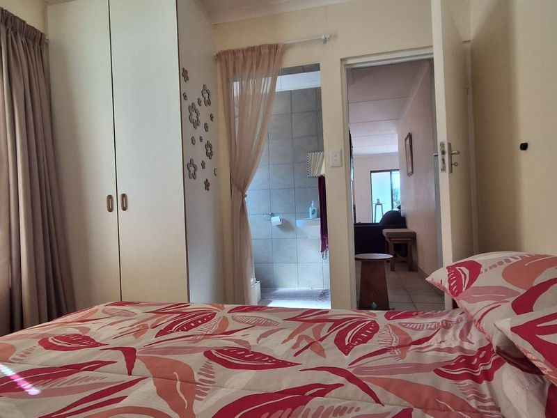A bedroom featuring built-in cupboards and an adjoining en-suite bathroom, providing a functional layout with natural light.