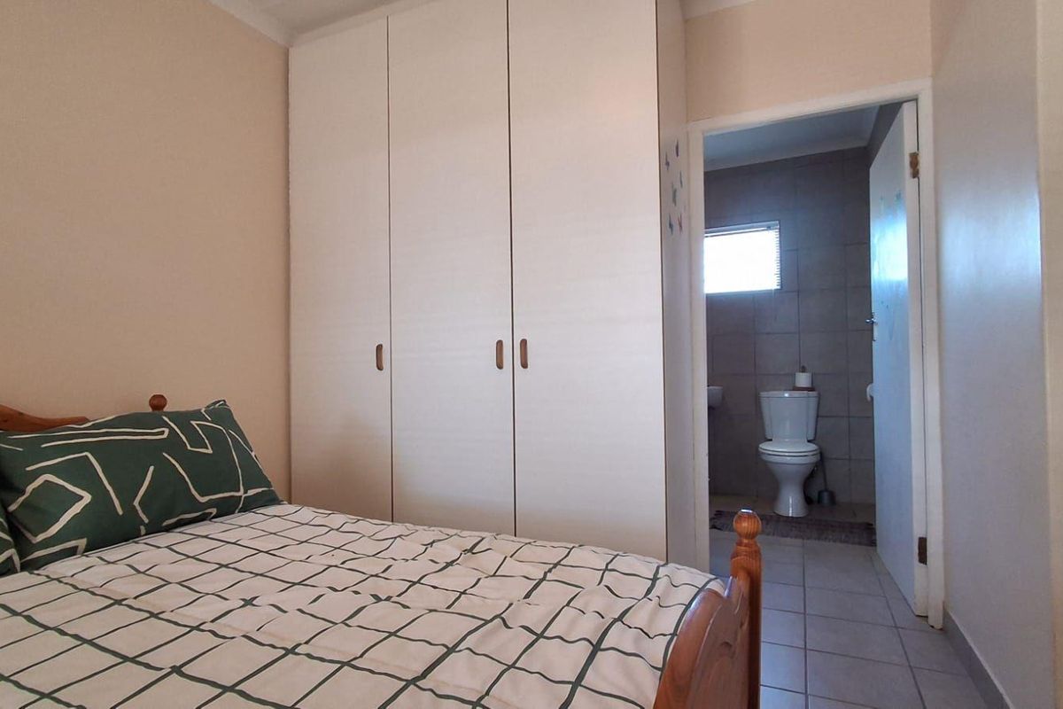 A bedroom featuring built-in cupboards and direct access to an en-suite bathroom with tiled flooring.