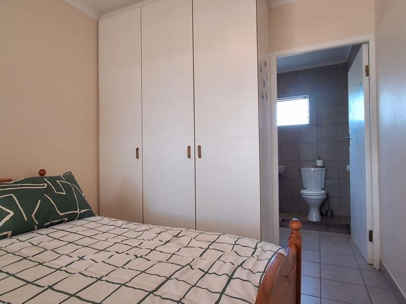 A bedroom featuring built-in cupboards and direct access to an en-suite bathroom with tiled flooring.