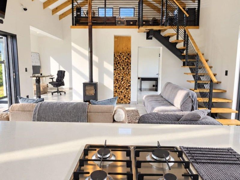 Spacious open-plan living area featuring a modern kitchen with stone countertops, a wood-burning fireplace, and a mezzanine level accessed by a feature staircase.
