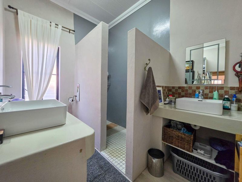Bathroom featuring a walk-in shower with tiled flooring, dual vessel sinks on built-in vanities, and mosaic tile backsplashes.