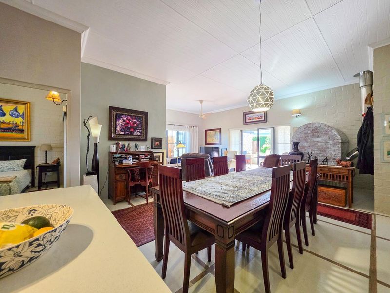 Spacious open-plan living and dining area featuring a brick fireplace, tiled flooring, and direct access to the outdoor patio through sliding glass doors.