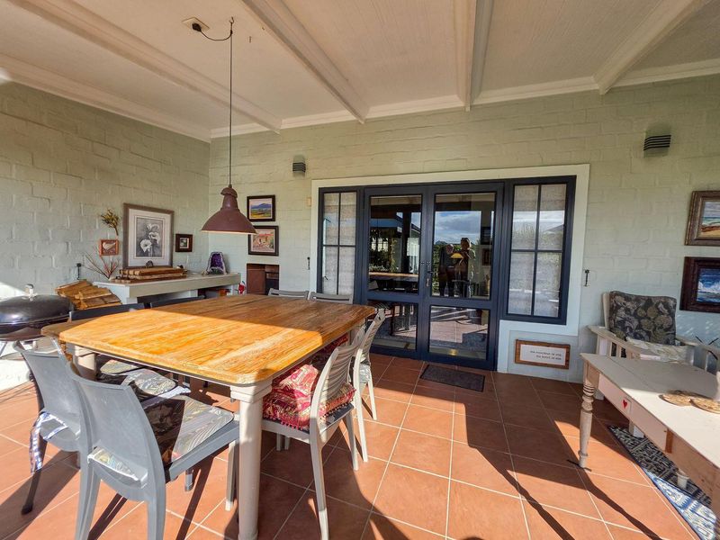 A covered patio area featuring tiled flooring, exposed beam ceilings, and a built-in masonry counter, providing a functional outdoor entertainment space.