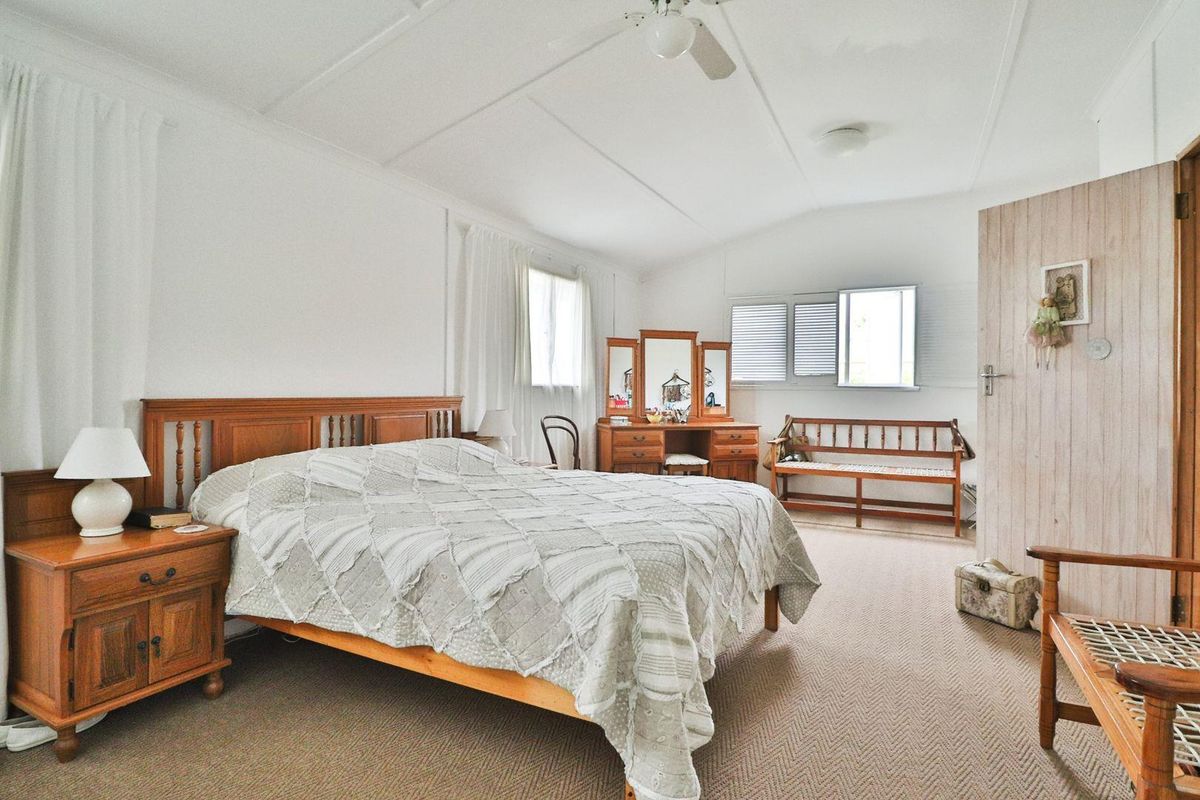 A spacious bedroom featuring neutral carpeted flooring, a ceiling fan, and classic casement windows, offering a comfortable and functional living space.