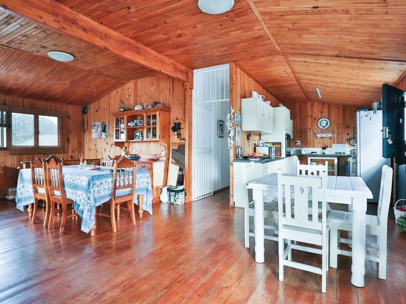 Open plan living and kitchen area featuring extensive timber wall paneling, vaulted timber ceilings, and hardwood flooring throughout.