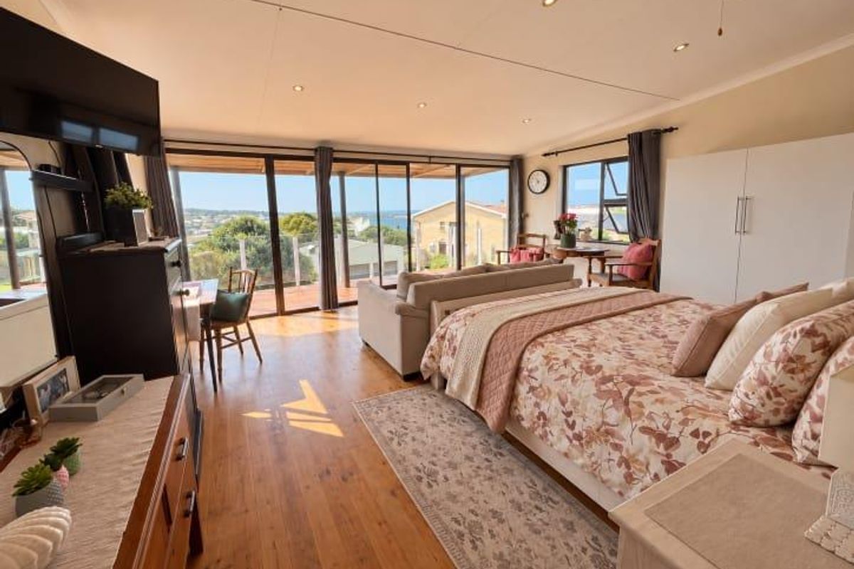 Spacious bedroom featuring hardwood flooring, recessed lighting, and large sliding glass doors that open to a scenic outdoor view.