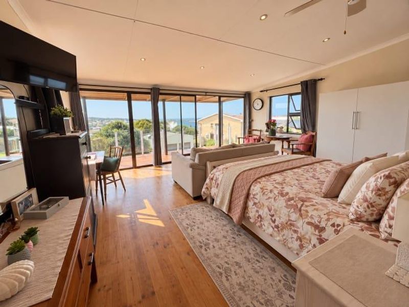 Spacious bedroom featuring hardwood flooring, recessed lighting, and large sliding glass doors that open to a scenic outdoor view.