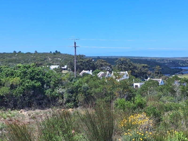 A scenic landscape view overlooking natural vegetation, distant residential properties, and a nearby river or estuary.