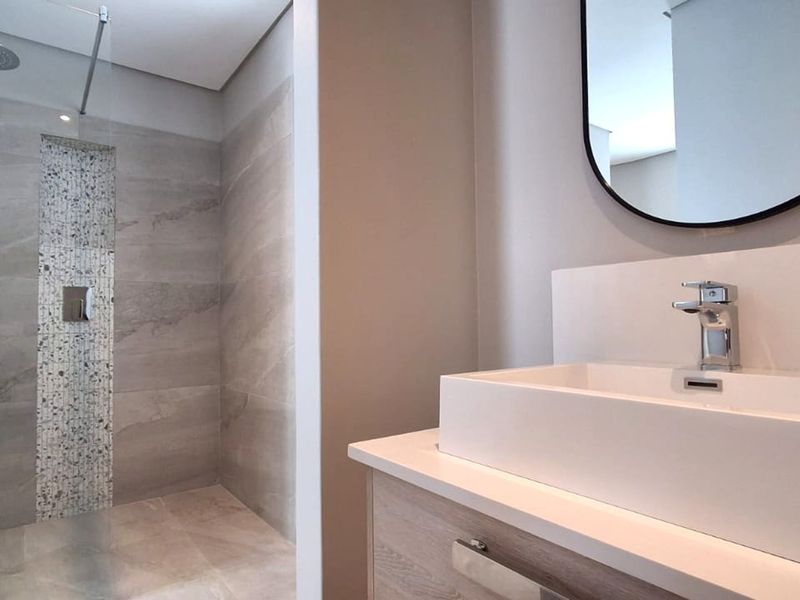 Modern bathroom featuring a walk-in shower with a rain shower head, mosaic tile accents, and a contemporary vanity with a vessel sink.