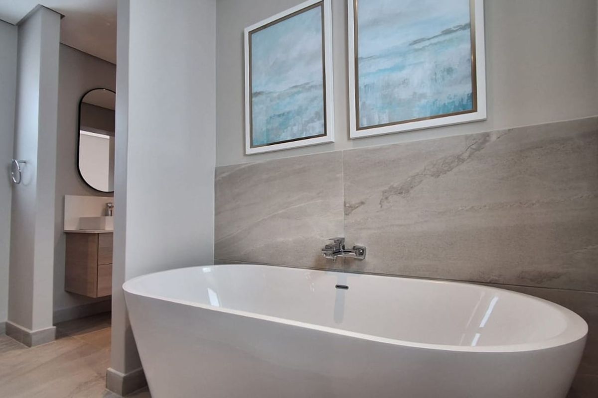 Modern bathroom featuring a sleek freestanding bathtub, stone-look wall tiles, and a floating vanity with a vessel sink.