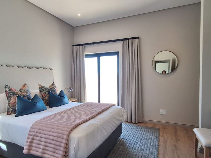 A well-maintained bedroom featuring laminate flooring, recessed lighting, and a sliding glass door providing natural light.