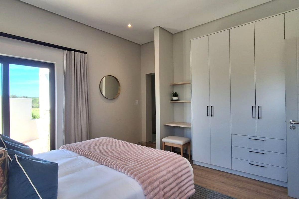Modern bedroom featuring extensive built-in cabinetry, a built-in vanity area, laminate flooring, and a sliding glass door providing natural light.