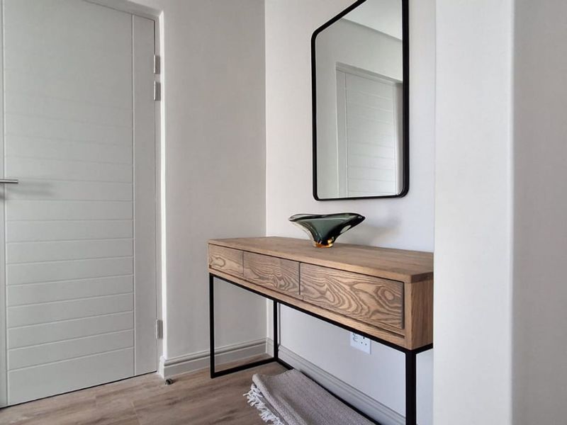 A clean and modern hallway featuring light-toned laminate flooring, neutral walls, and a contemporary internal door.