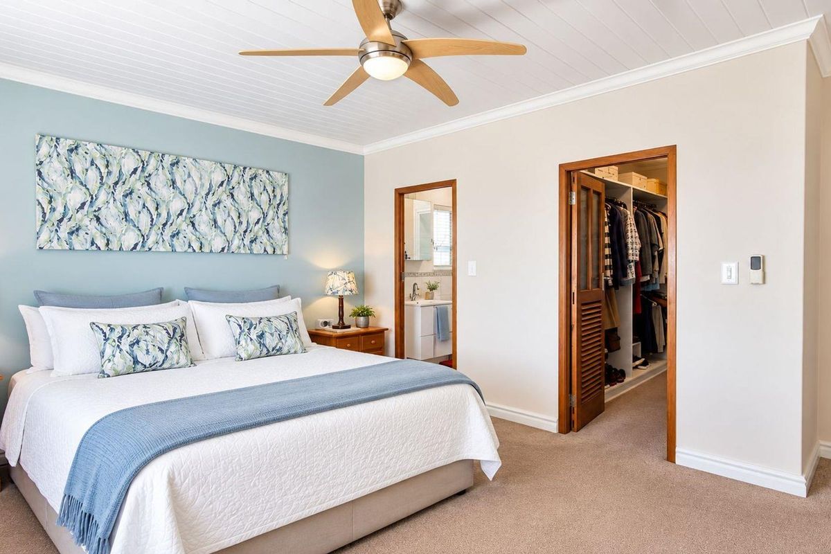 Spacious bedroom featuring a tongue and groove ceiling, ceiling fan, carpeted flooring, and direct access to a walk-in closet and en-suite bathroom.