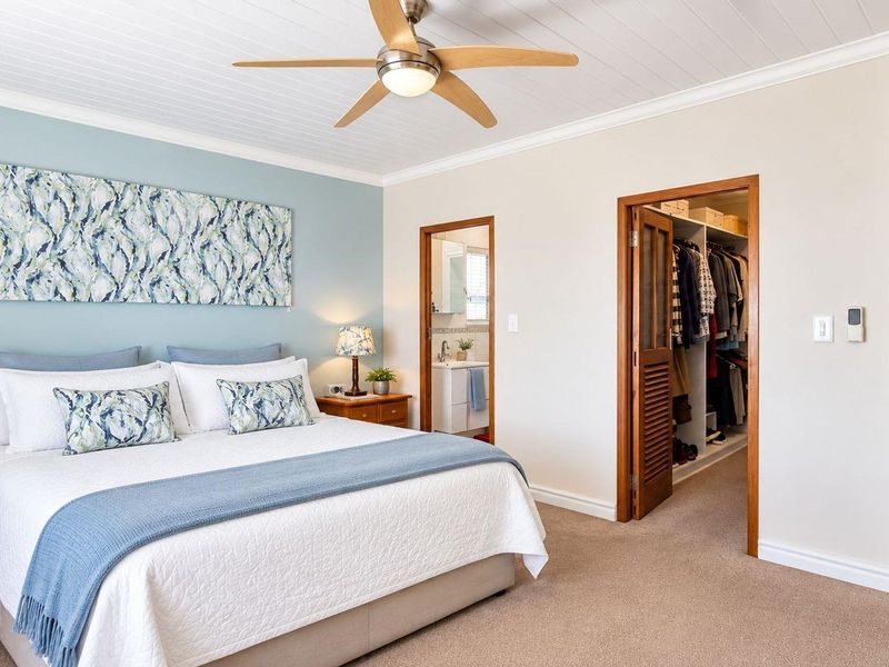 Spacious bedroom featuring a tongue and groove ceiling, ceiling fan, carpeted flooring, and direct access to a walk-in closet and en-suite bathroom.