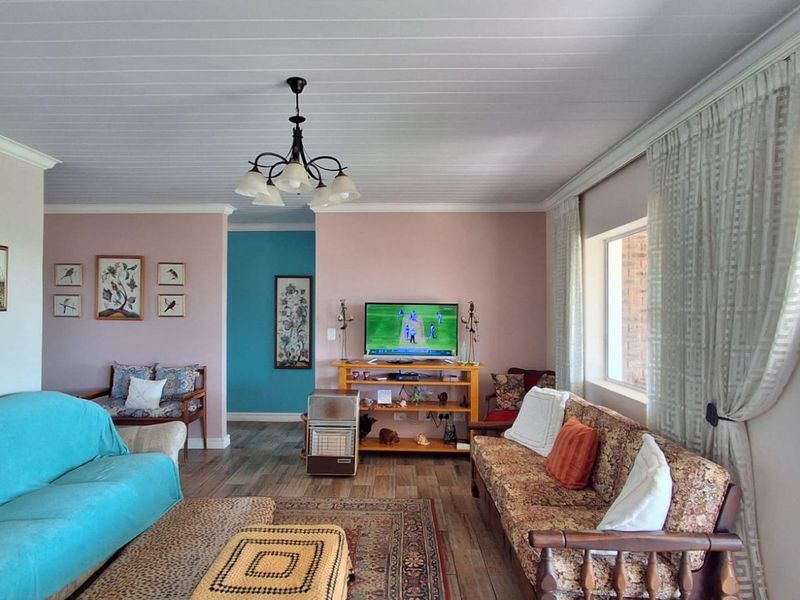 A spacious living room featuring timber-look flooring, a tongue and groove ceiling, and a sliding glass door providing access to the outdoor area.