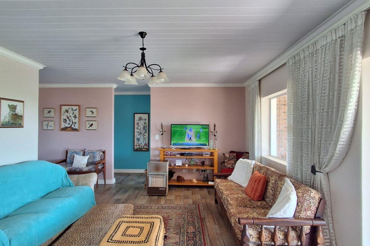 A spacious living room featuring timber-look flooring, a tongue and groove ceiling, and a sliding glass door providing access to the outdoor area.
