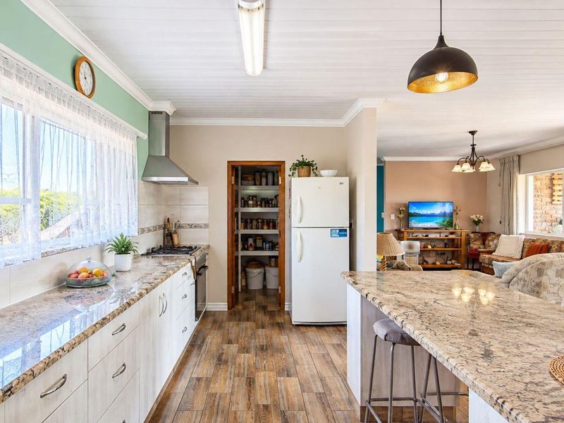 Spacious open-plan kitchen and living area featuring granite countertops, a built-in oven, gas hob, and a convenient walk-in pantry.