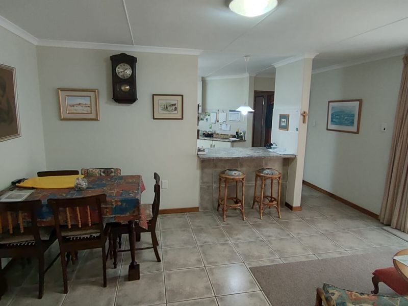 Open plan living and dining area featuring tiled flooring, a breakfast bar, and access to a patio through sliding glass doors.
