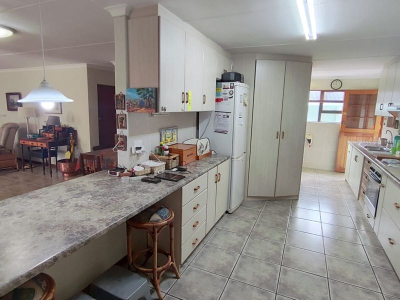 Open plan kitchen featuring laminate cabinetry, stone-look countertops, and ceramic floor tiles, seamlessly flowing into the adjacent living and dining area.
