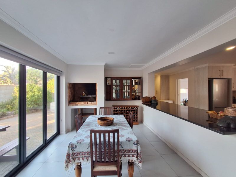 Open-plan living and dining area featuring a built-in braai, sleek granite kitchen counters, and large sliding doors providing seamless access to the outdoor patio.