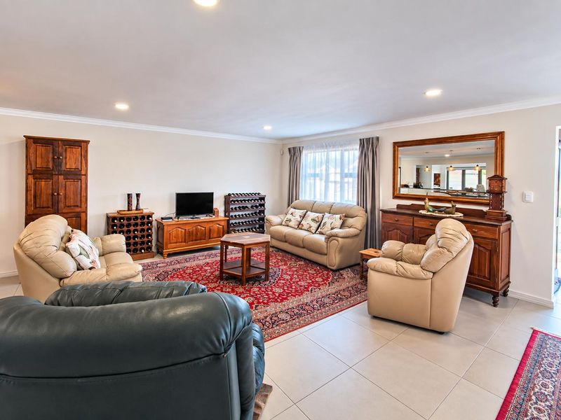 Spacious living room featuring neutral tiled flooring, recessed downlighting, and classic cove cornicing, providing a comfortable and well-maintained area for relaxation.