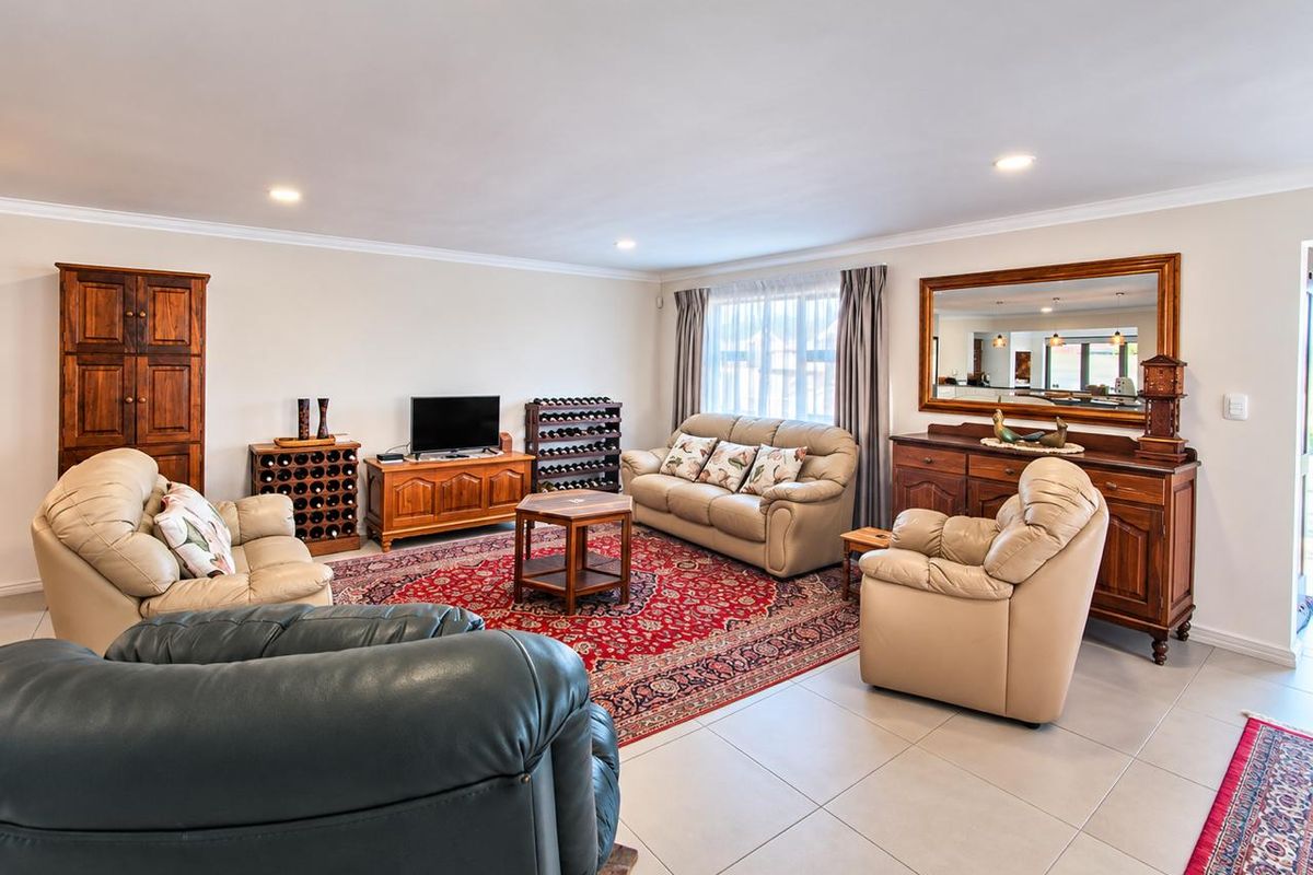 Spacious living room featuring neutral tiled flooring, recessed downlighting, and classic cove cornicing, providing a comfortable and well-maintained area for relaxation.