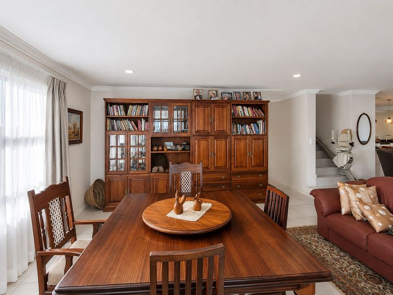 Open plan living and dining area featuring built-in wooden cabinetry, tiled flooring, and a staircase equipped with a stair lift.
