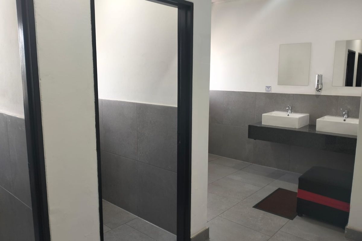 Modern office bathroom featuring dual vanity basins, sleek grey wall tiling, and clean, minimalist finishes.