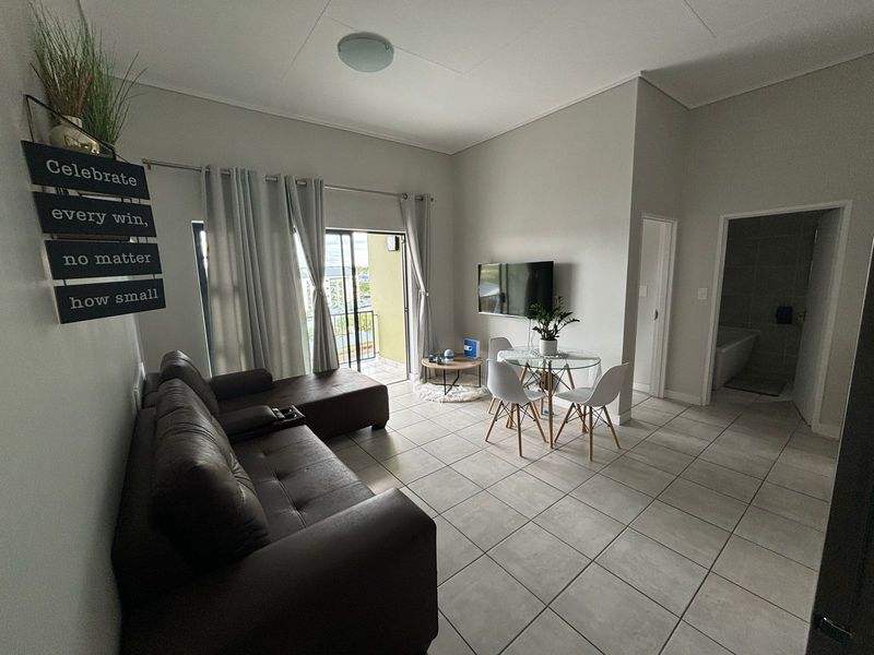 Open-plan living and dining area featuring neutral tiled flooring, high ceilings, and direct access to a private balcony.
