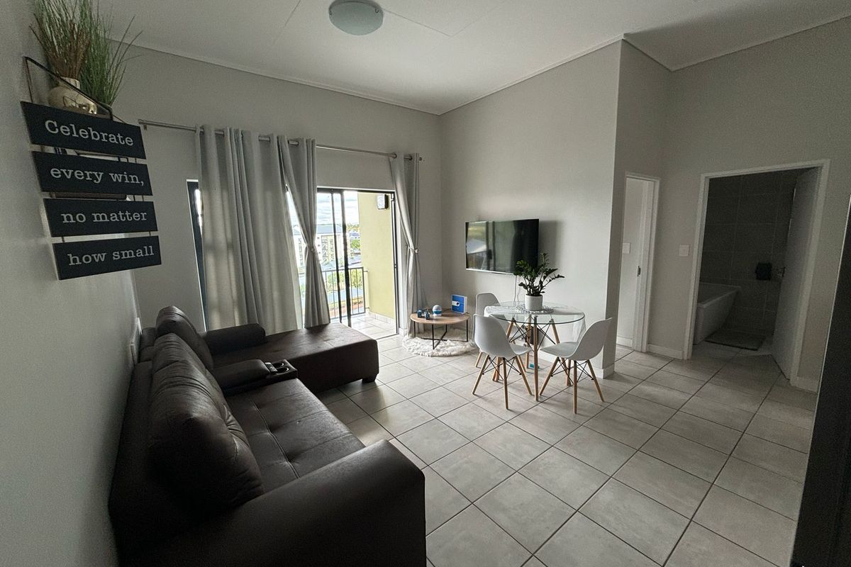 Open-plan living and dining area featuring neutral tiled flooring, high ceilings, and direct access to a private balcony.