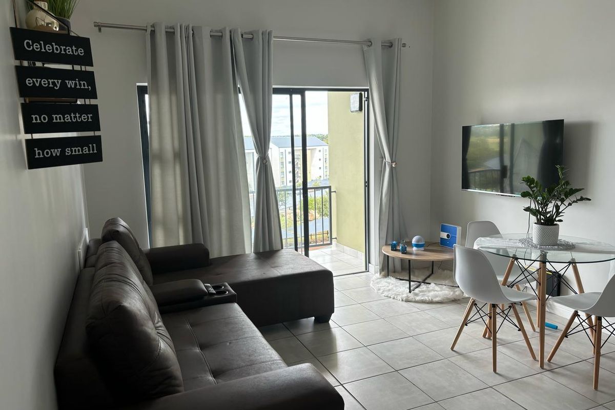 Open-plan living and dining area featuring tiled flooring and direct access to a private balcony through sliding glass doors.